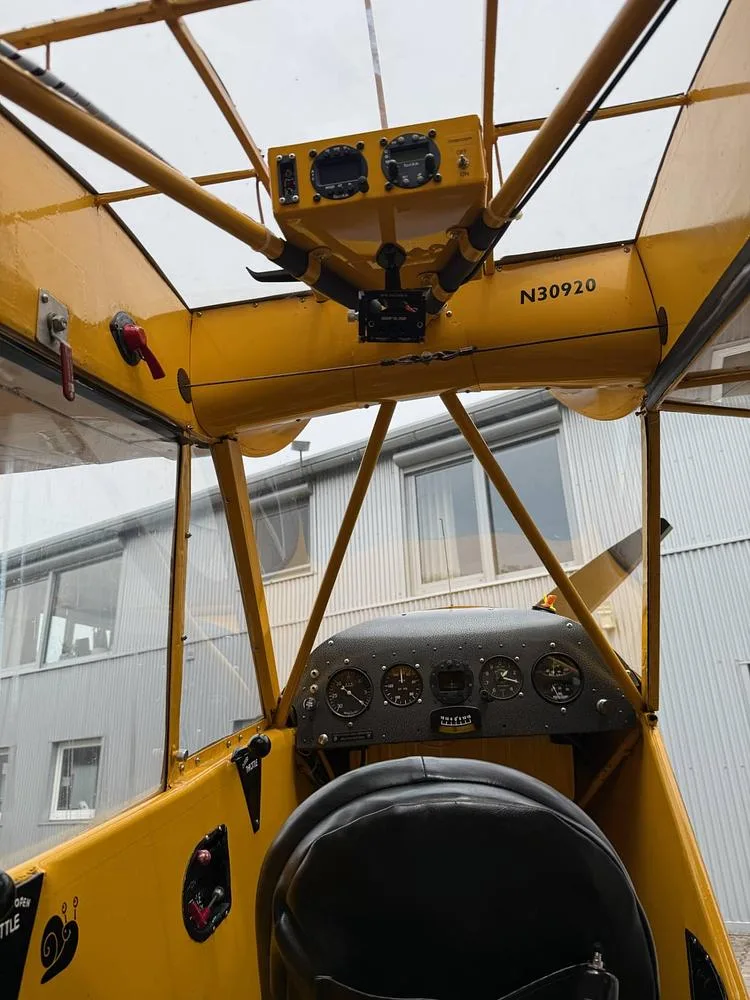 View from the cockpit of a yellow aircraft, showing the instrument panel, overhead controls, and the registration N30920 on the frame.