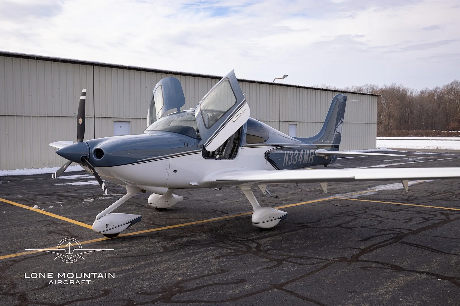 A front-side view of the Cirrus SR20 aircraft, N334MR, with its gull-wing doors open.