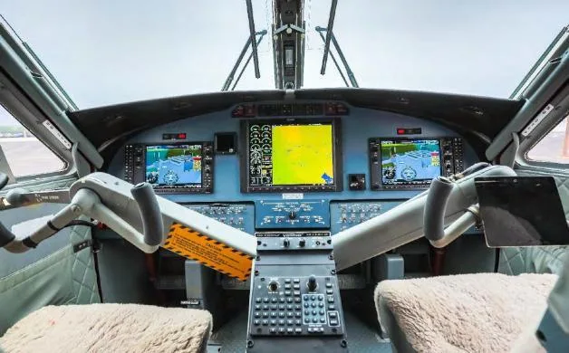 The cockpit of an aircraft showing the instrument panel with multiple digital displays, control yokes, and center console.