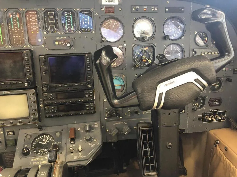 A detailed view of the aircraft's cockpit instrument panel, featuring analog gauges, digital displays, and a Cessna branded control yoke.
