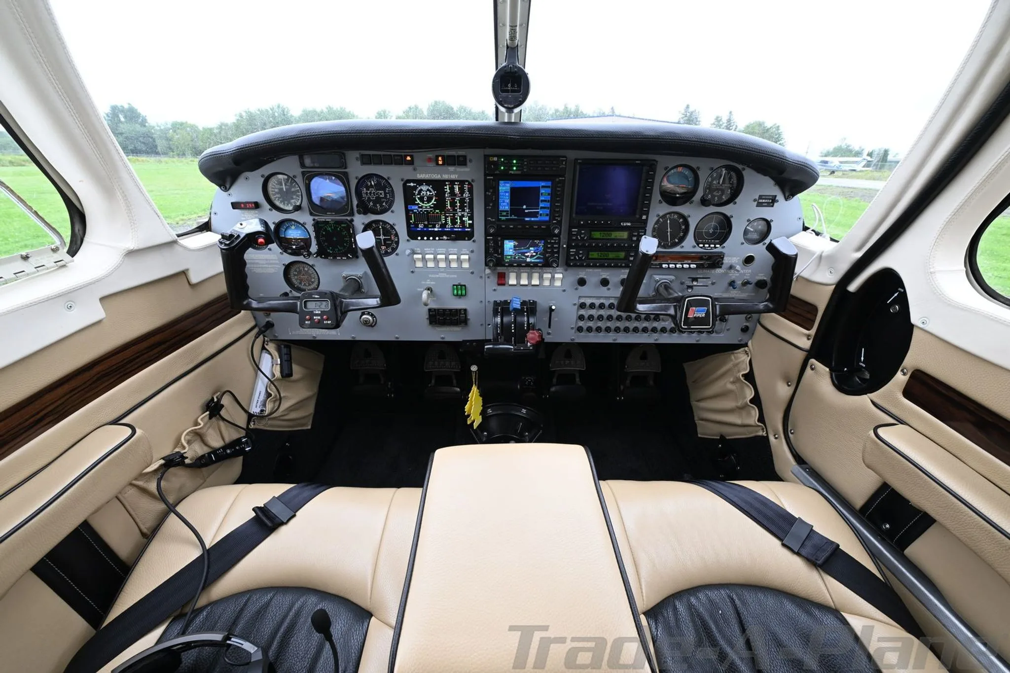 A wide view of the Piper Saratoga cockpit, featuring a glass panel and tan and black leather seats.
