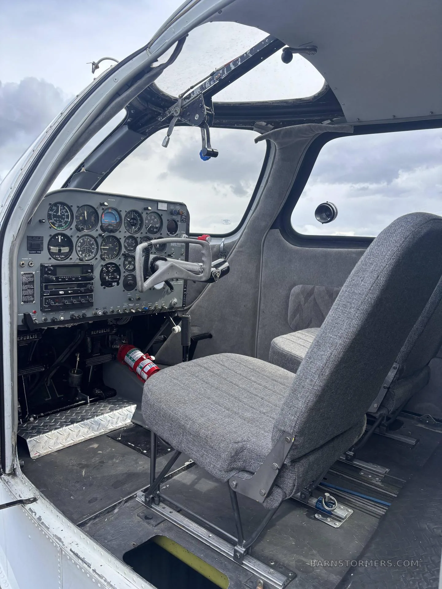 The cockpit of a Republic RC-3 Seabee showing the instrument panel, yoke, and gray fabric pilot's seat.
