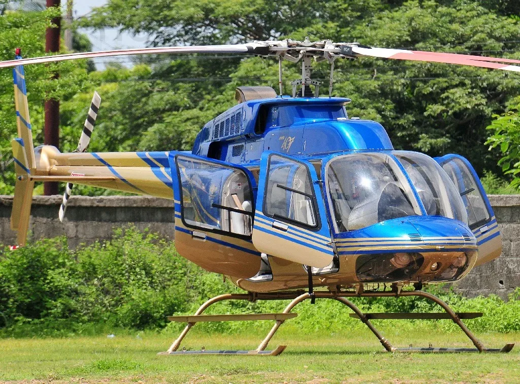 A blue and gold helicopter with its doors open is parked on a grassy field.