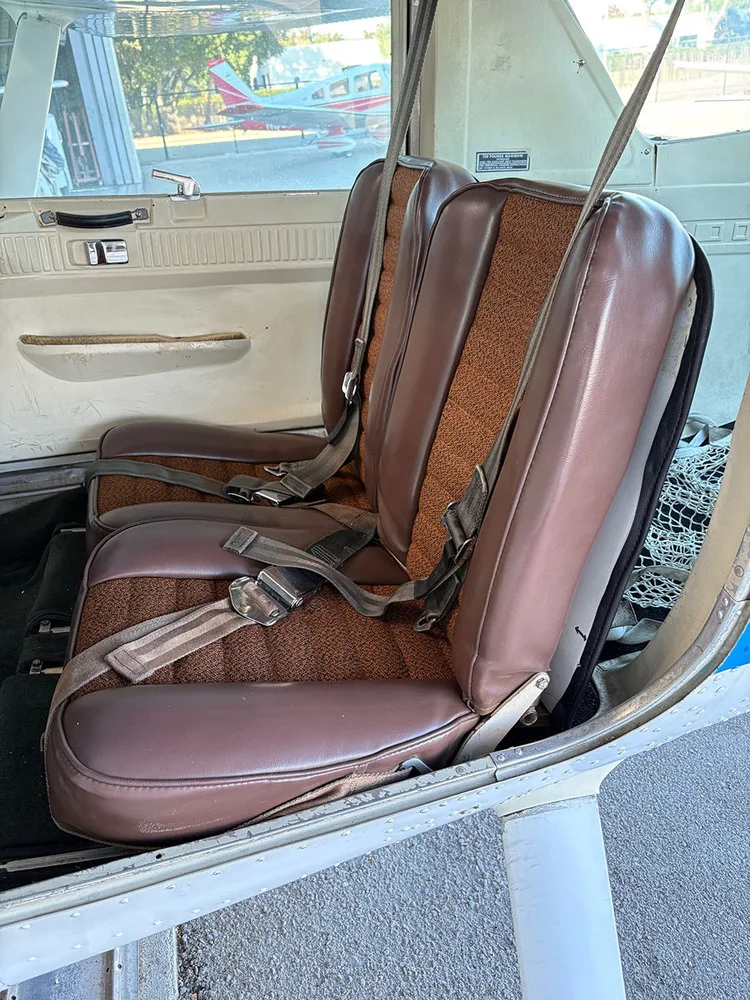 The brown and orange fabric and vinyl seats in the cabin of a small aircraft.