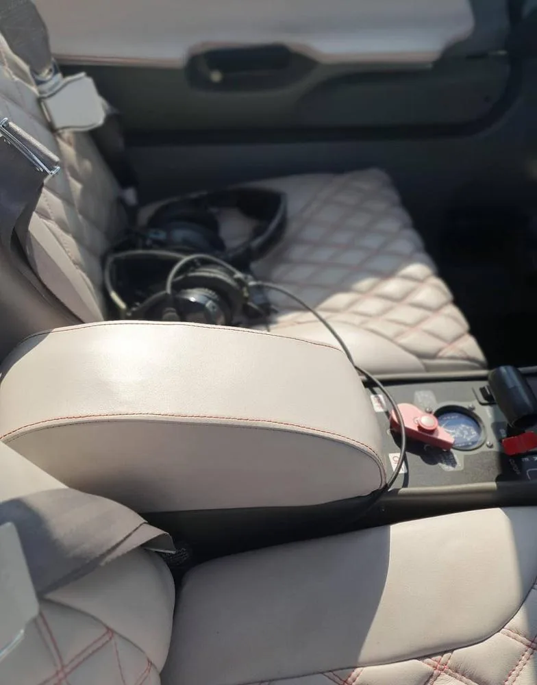 The light-colored quilted leather interior seats of an aircraft with headphones resting on one seat.