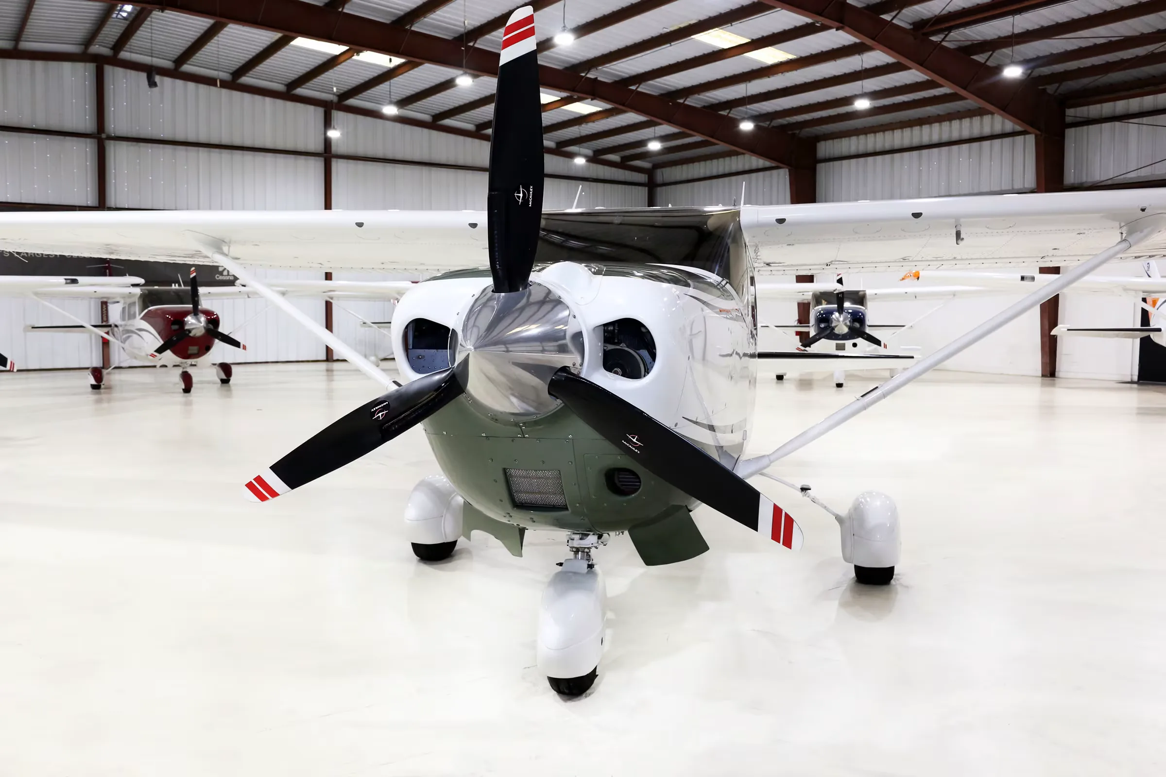 Front view of a white and green Cessna Stationair TC, registration N669DB, with its propeller, parked in a hangar.
