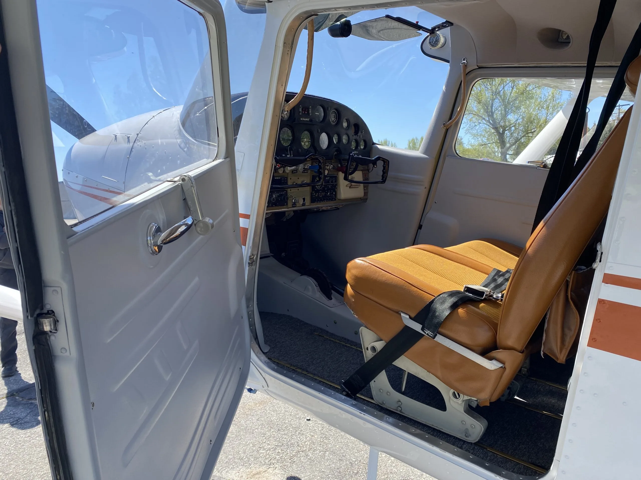 View into the cockpit and cabin of a Cessna 170B, showing the instrument panel and a brown seat.