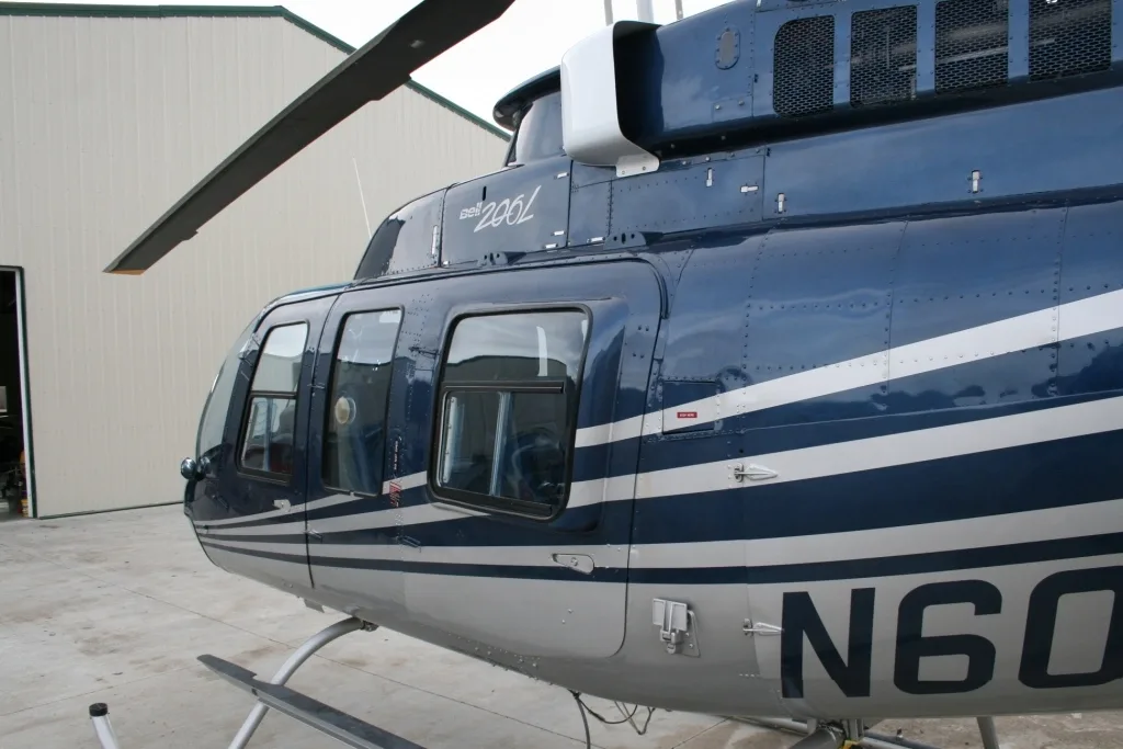 Close-up side view of the blue and white Bell 206L helicopter (N60VG) showing the cabin windows and paint scheme.