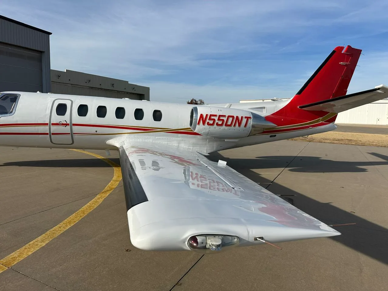 Side view of Cessna Citation CJ1+ aircraft N550NT with red and gold accents.