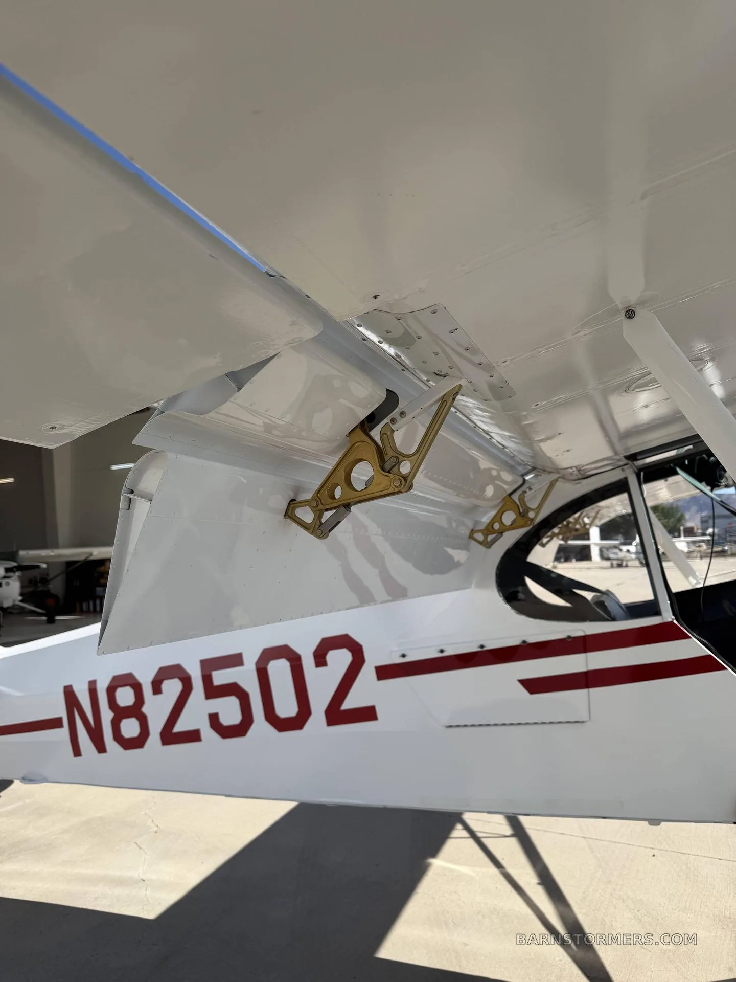 A close-up view of the white wing and fuselage of a bush plane, showing the N-number and wing flap mechanism.