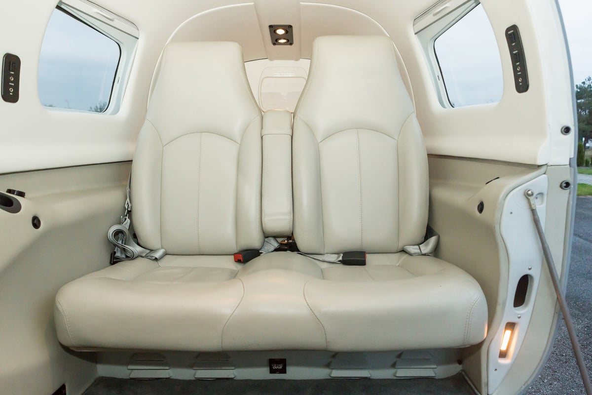 The rear seats of an aircraft are upholstered in light-colored leather.