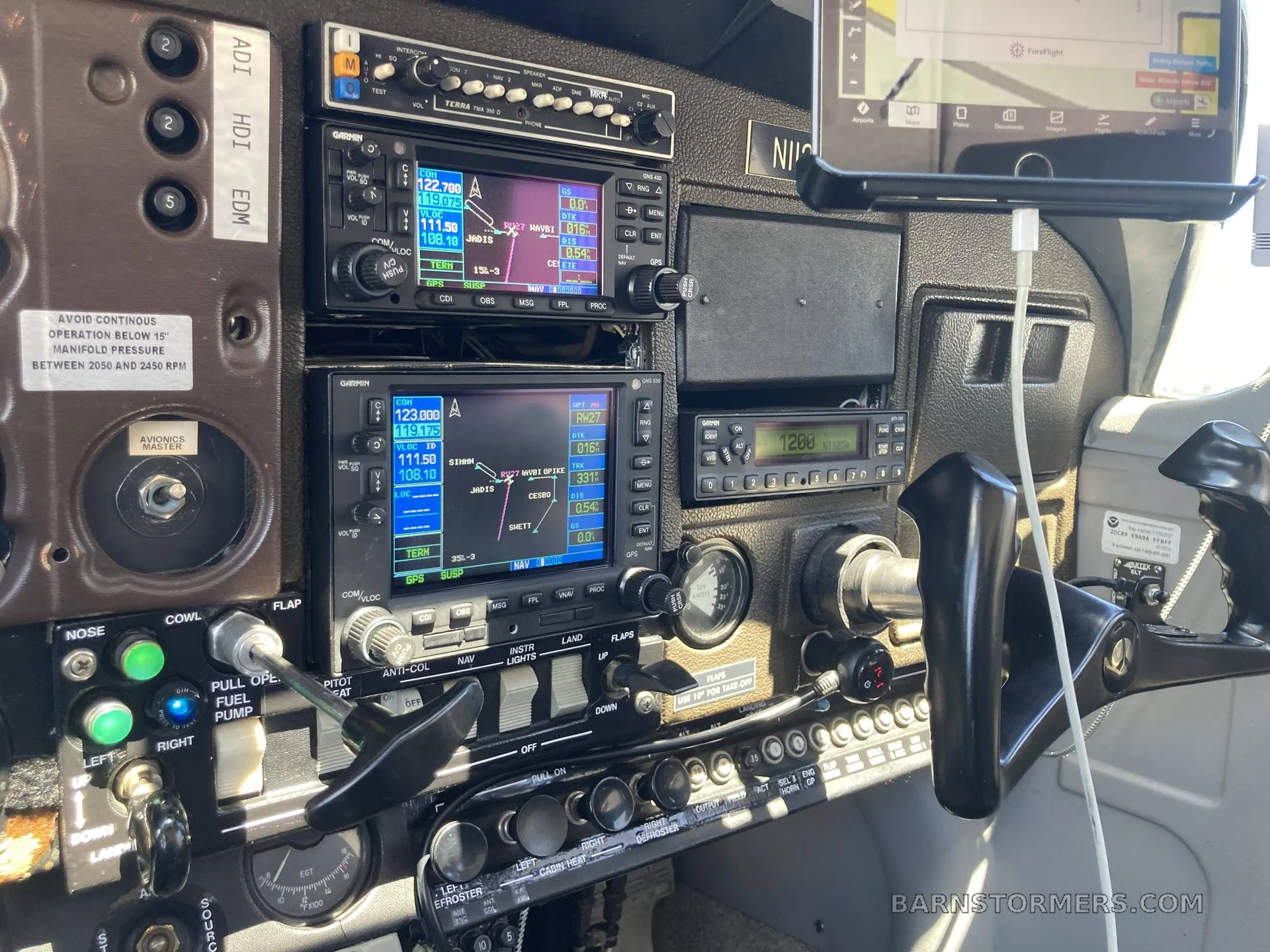 A close-up view of an aircraft's avionics stack and control panel, showing multiple Garmin displays and switches.
