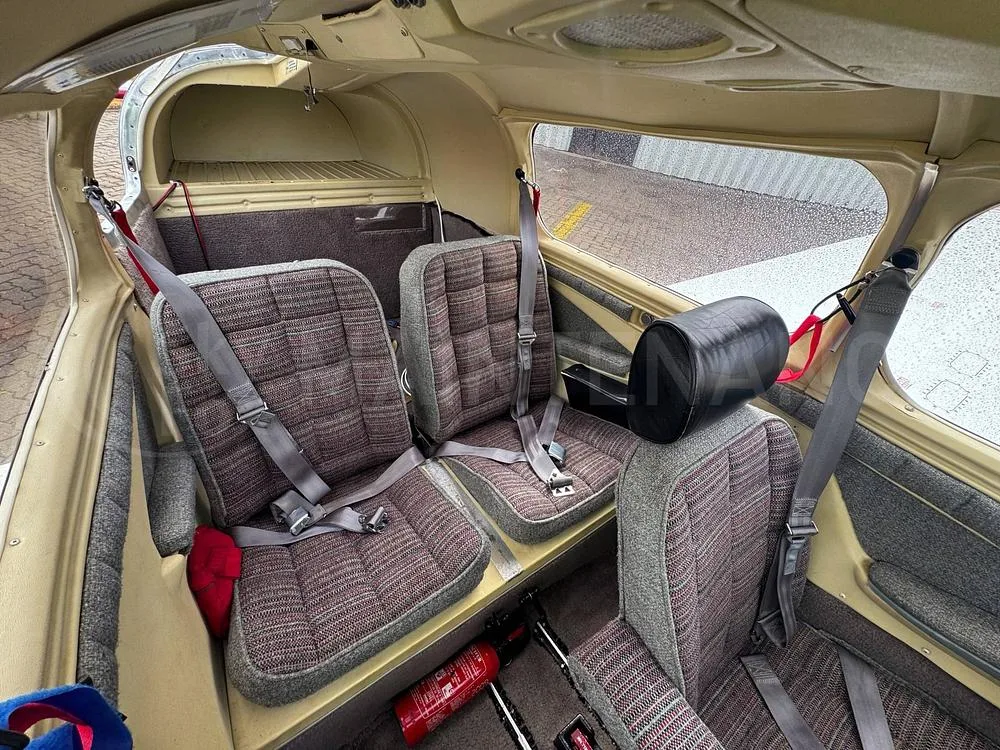 The rear cabin interior of the aircraft, showing two rows of seats with grey and red patterned upholstery.