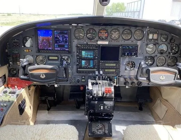 The cockpit of a Cessna 414 Chancellor aircraft, featuring a mix of analog gauges and modern digital displays, with dual yokes and a central throttle quadrant.