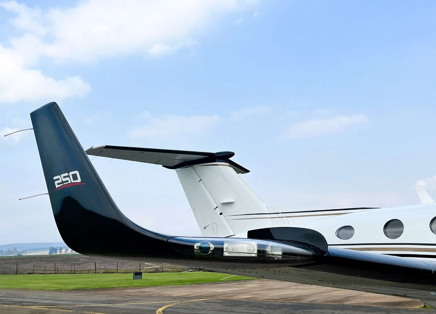 A close-up view of the black tail and wingtip of a Beechcraft King Air 250 aircraft on the tarmac.