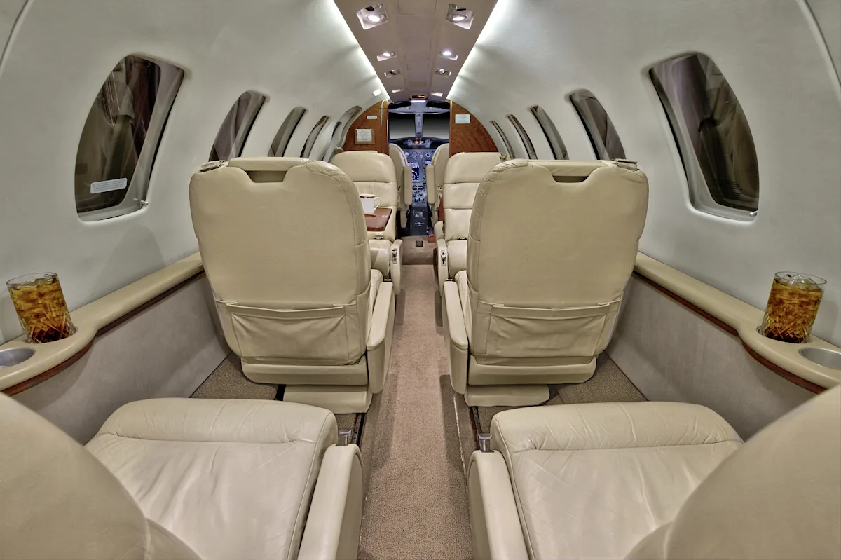 Aircraft interior with tan leather seats and a view towards the cockpit.