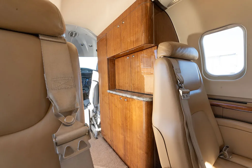 Interior view showing a wooden cabinet/galley area and beige leather cabin seats.