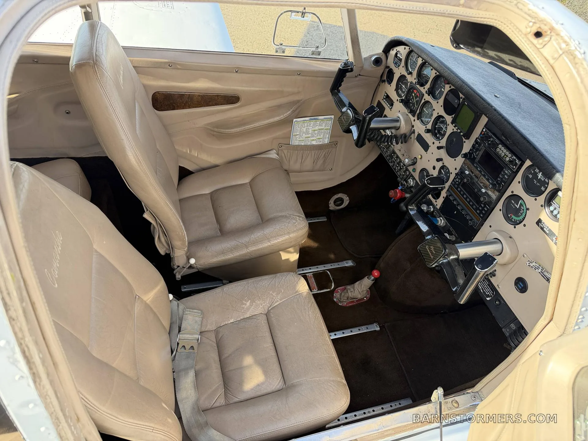 The tan leather front seats and a partial view of the instrument panel are visible inside a small aircraft cabin.