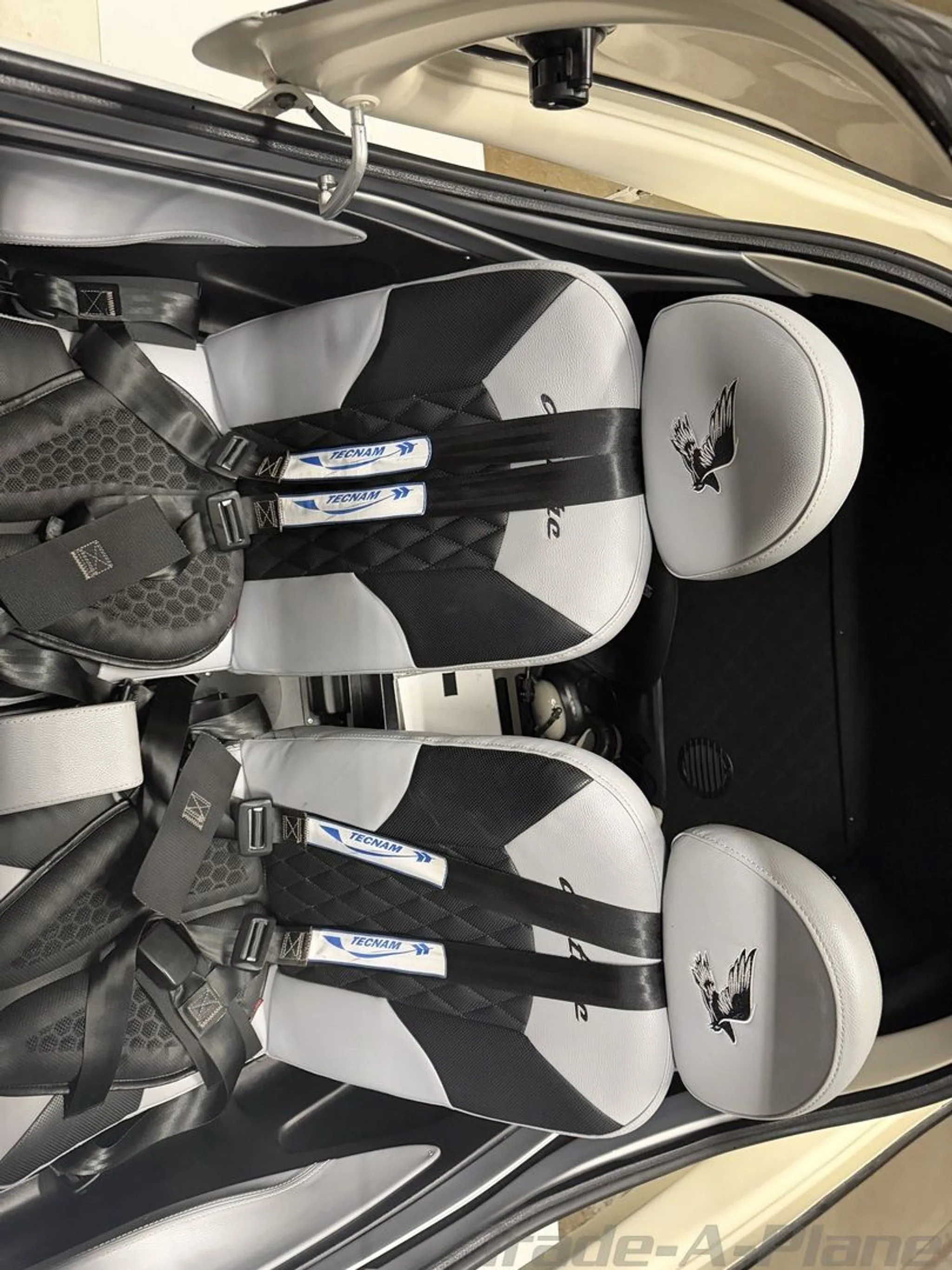 Overhead view of the two-tone black and grey seats with "Tecnam" branded harnesses in the aircraft cabin.