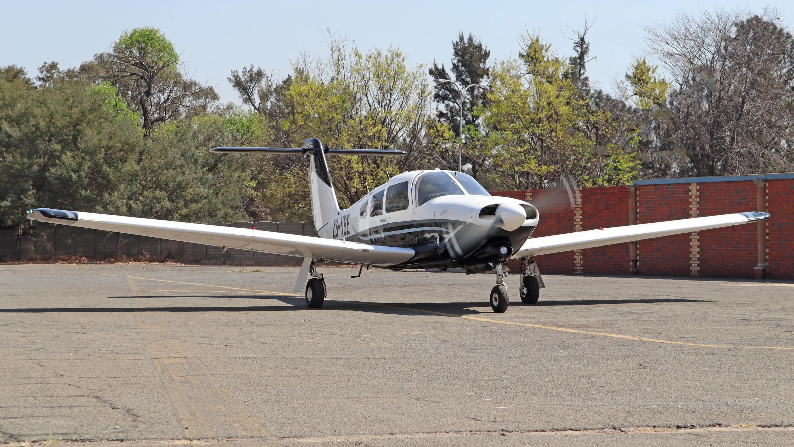 A white and black Piper PA-28-201T Turbo Arrow IV aircraft parked on an asphalt ramp.