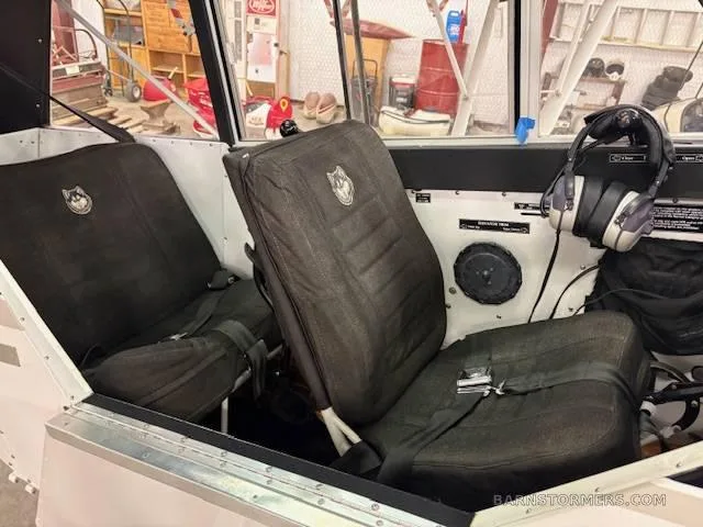 The interior cabin of the Aviat Husky A-1B, showing two dark grey fabric seats with a husky logo.