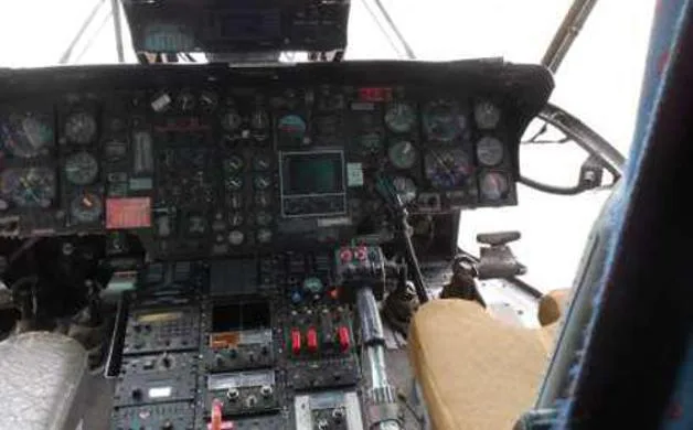 The cockpit of a helicopter, showing a complex array of analog gauges and digital screens.