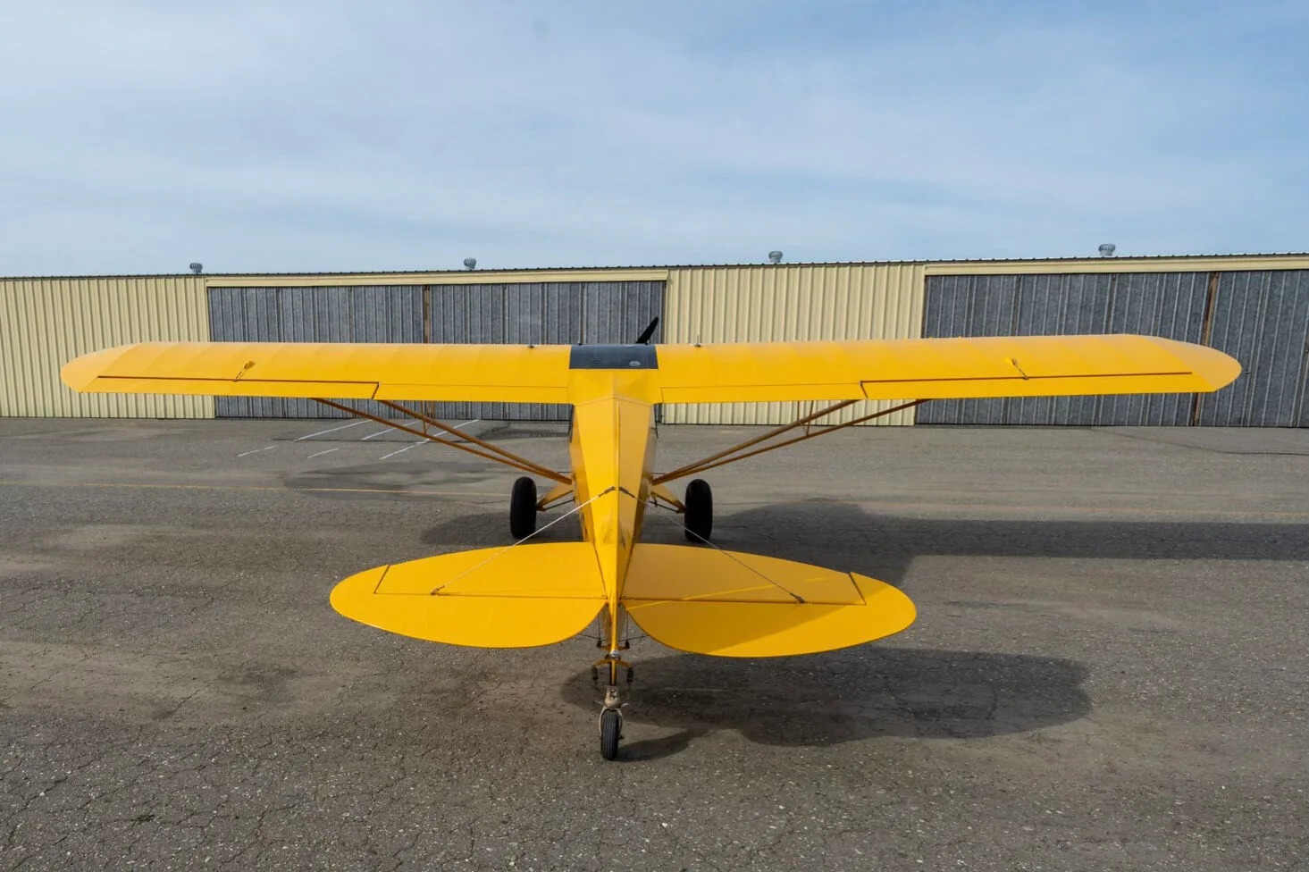 A rear view of the yellow CubCrafters Sport Cub S2 aircraft N579CC parked on an airfield.