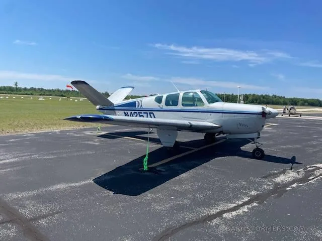 A white and blue single-engine aircraft (N4257D) parked on an asphalt ramp under a clear blue sky.