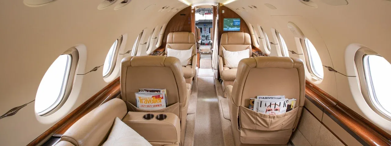 The interior of a private jet with leather seats and magazines.