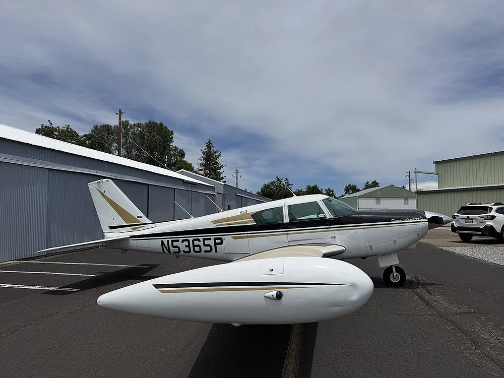 Side view of a white and black Piper Comanche 250, registration N5365P, parked on an airfield.