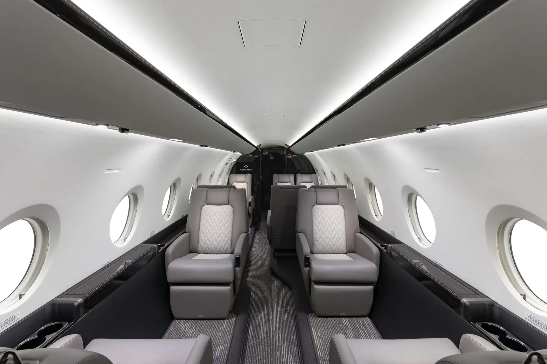 Forward view of the aircraft cabin with leather seats and oval windows.