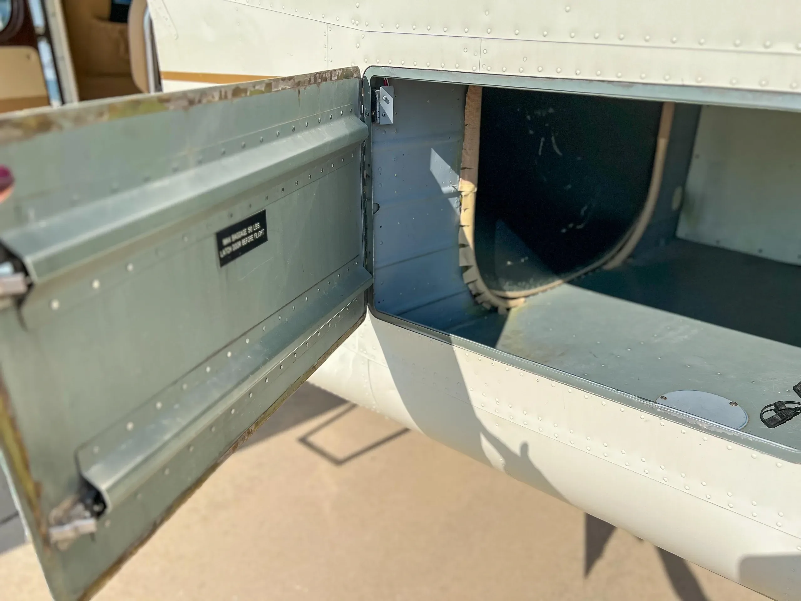 An open baggage compartment on the side of the aircraft's fuselage, revealing its interior.