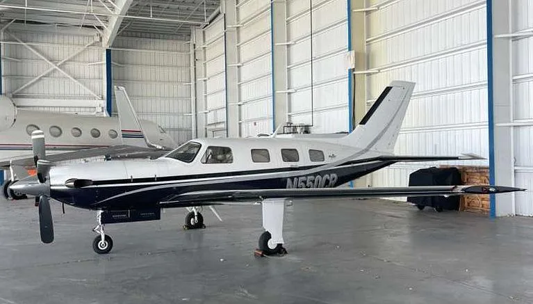A Piper M500 aircraft with a silver and dark blue paint scheme, registration N550CR, parked in a hangar.