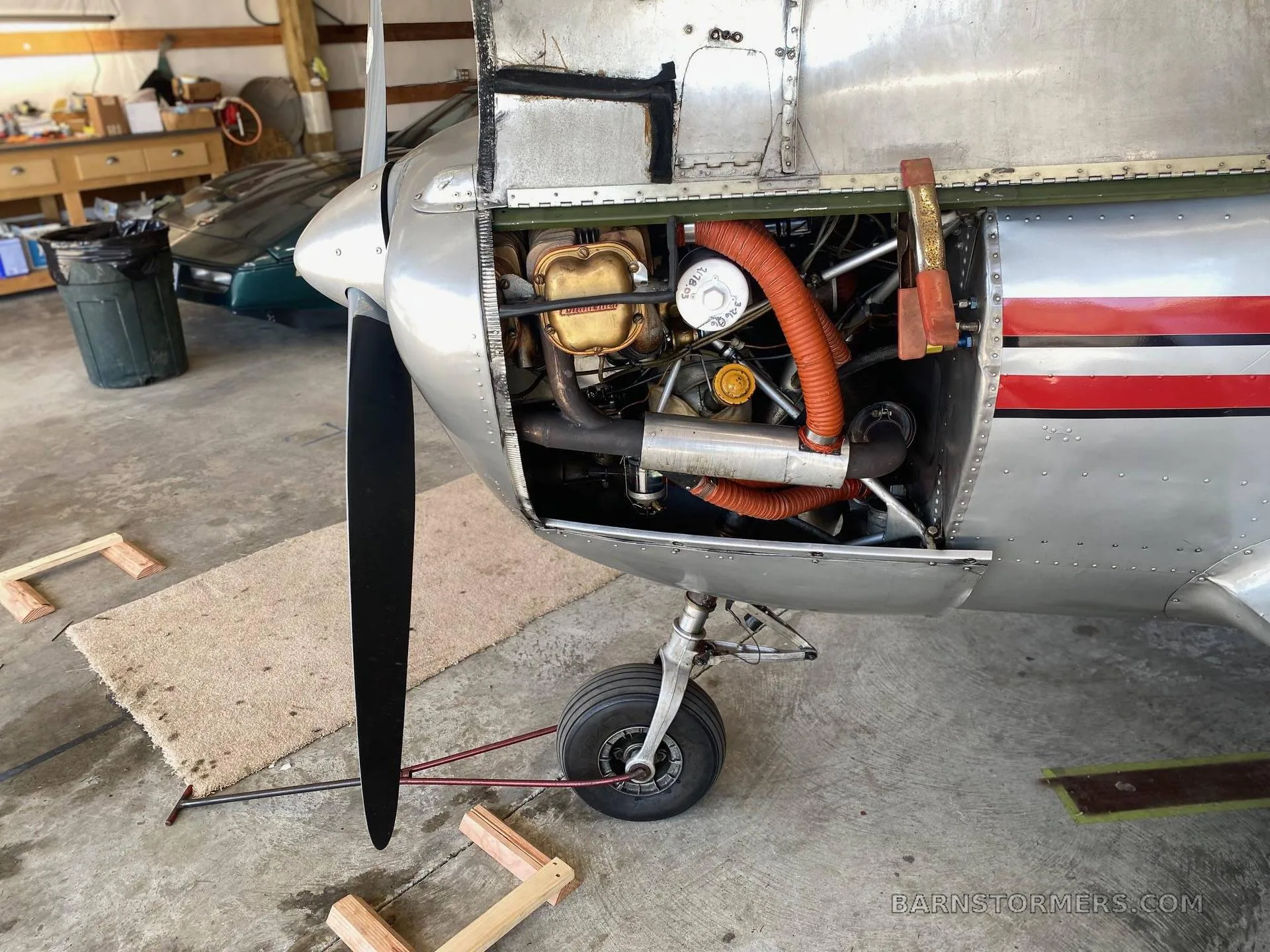 The engine compartment of a silver Ercoupe aircraft with the cowling removed, revealing the engine and components.