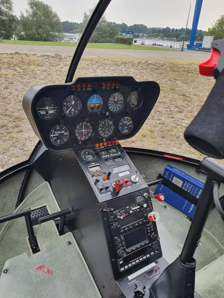 The cockpit of a Robinson R44 Raven II helicopter, showing the instrument panel and controls.
