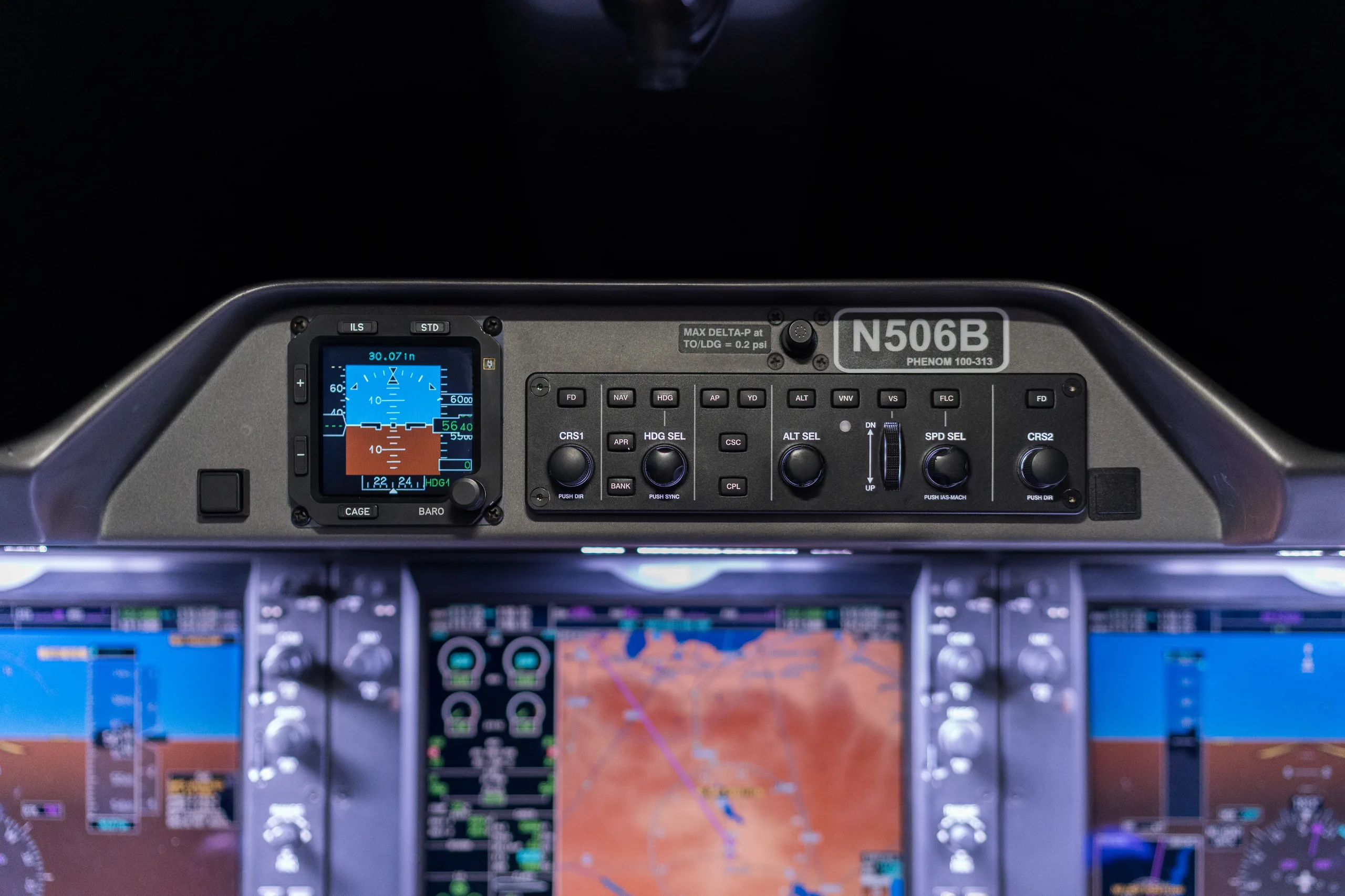 A close-up view of the overhead panel in an Embraer Phenom 100 cockpit, displaying flight instruments and controls, with registration N506B visible.