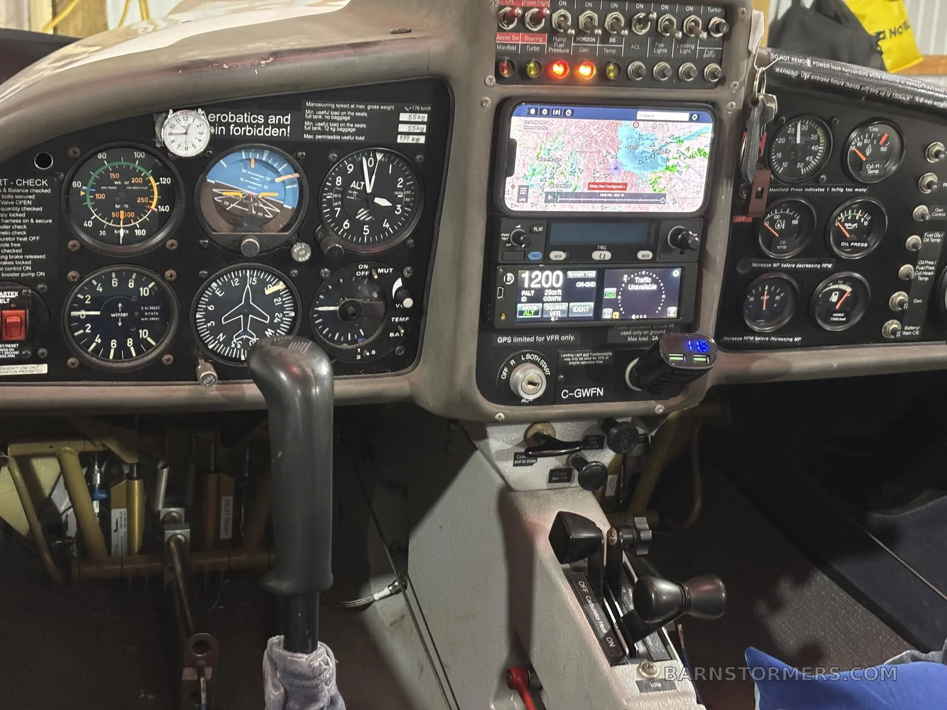 The cockpit of a glider, featuring analog instruments, a smartphone-based GPS display, and flight controls.