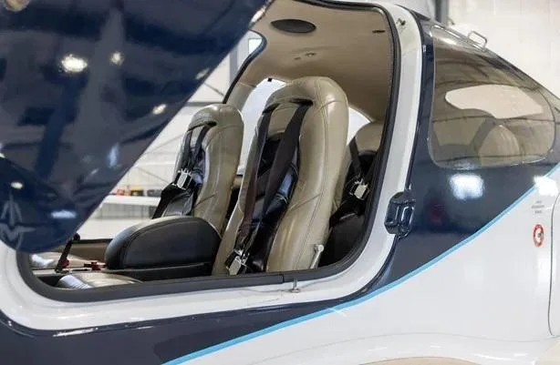 The tan leather interior seats of a dark blue and white aircraft, viewed through the open door.