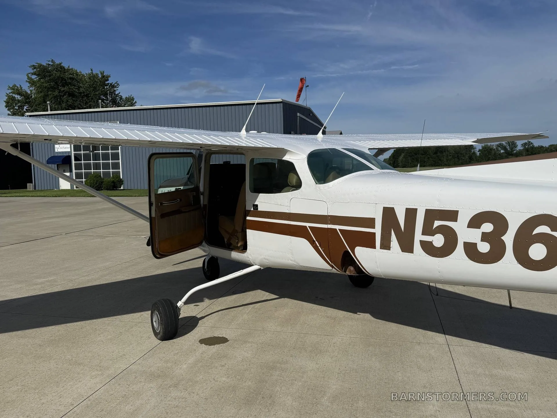 A close-up front-side view of a white and brown Cessna Cutlass RG II (N5369R) with its door open, parked on an airfield.