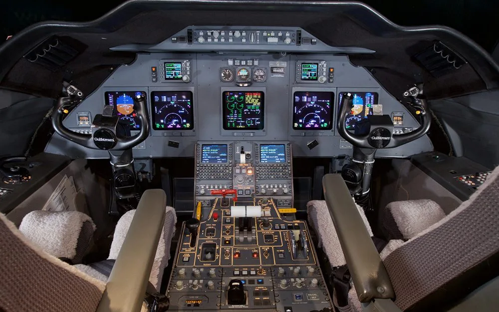 The cockpit of a business jet with multiple digital displays and control panels.