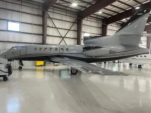 A grey business jet with black accents is parked inside a hangar.