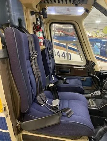 The front cabin interior of the helicopter showing two blue fabric pilot seats and controls.