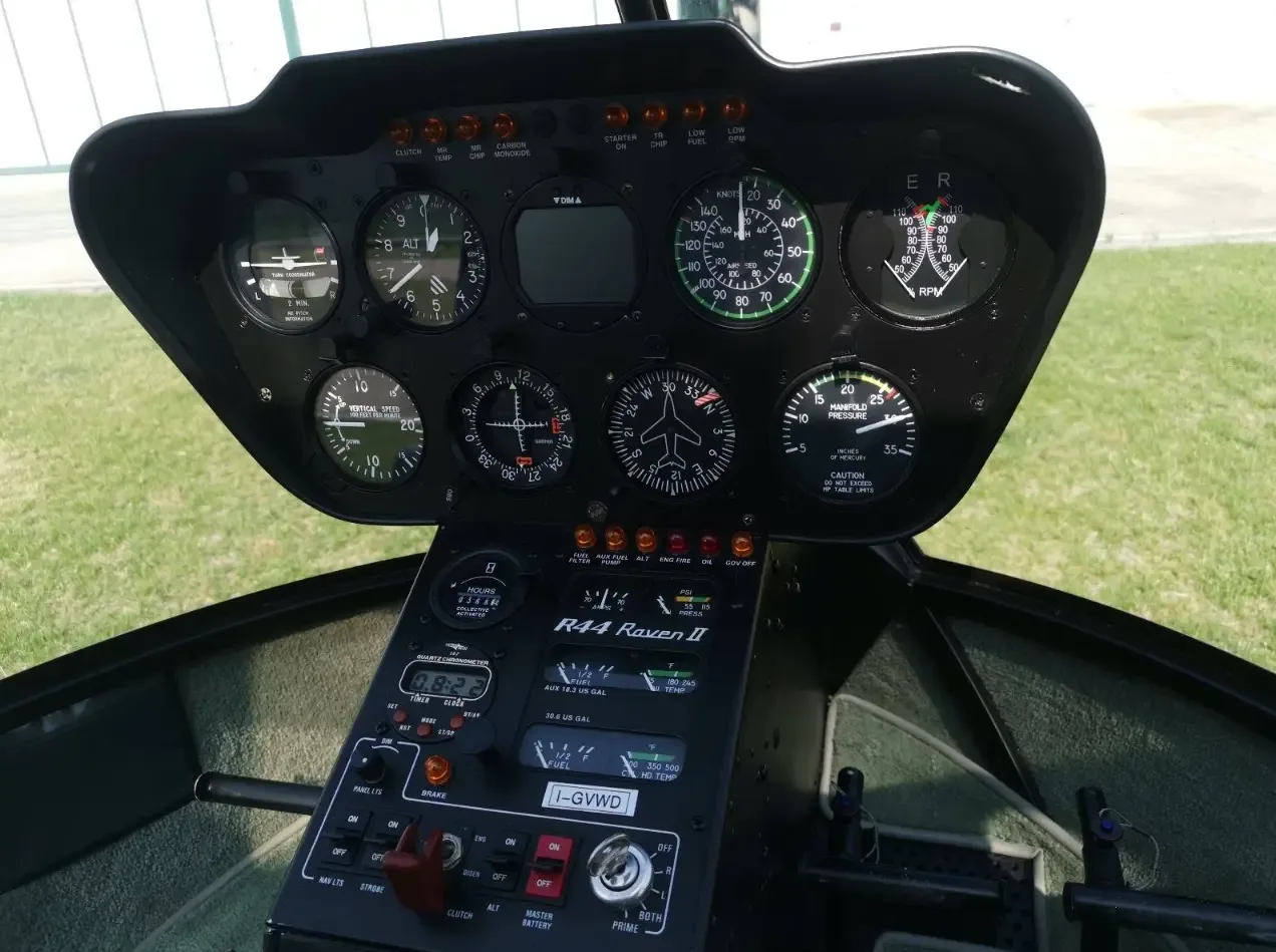 A detailed view of the instrument panel of a Robinson R44 Raven II helicopter, showing gauges and avionics.