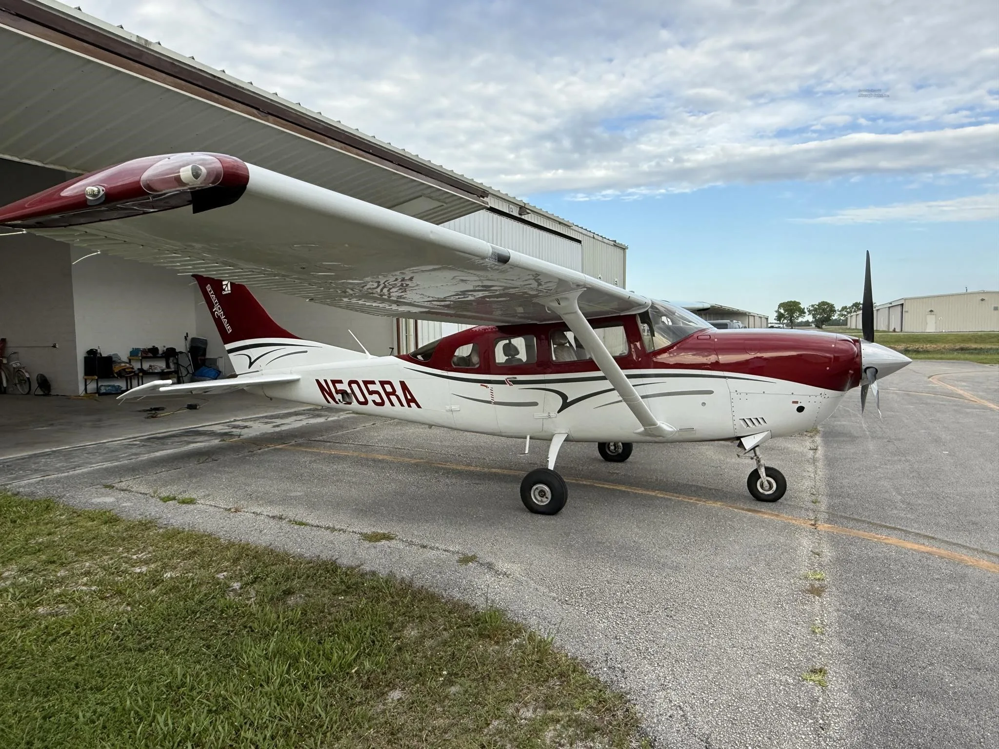 A red and white Cessna Stationair TC aircraft (N505RA) parked partially in a hangar, viewed from the rear left.