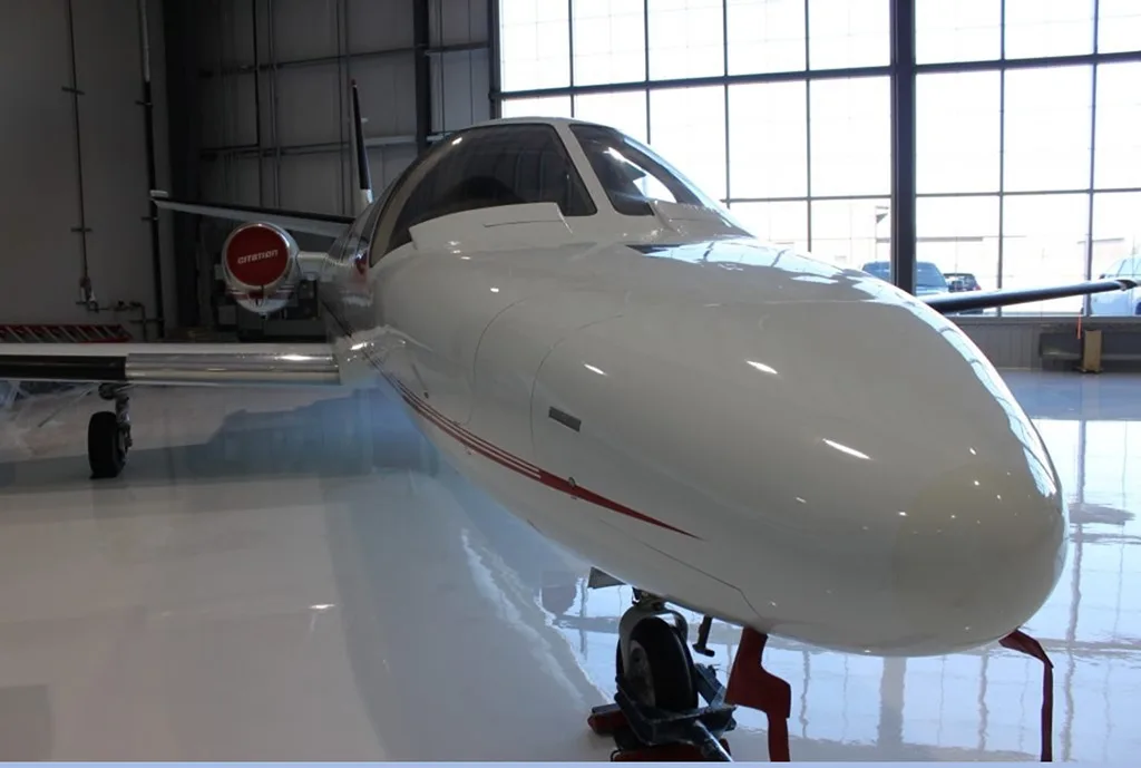 A close-up front view of the white nose of a Cessna Citation aircraft in a hangar.