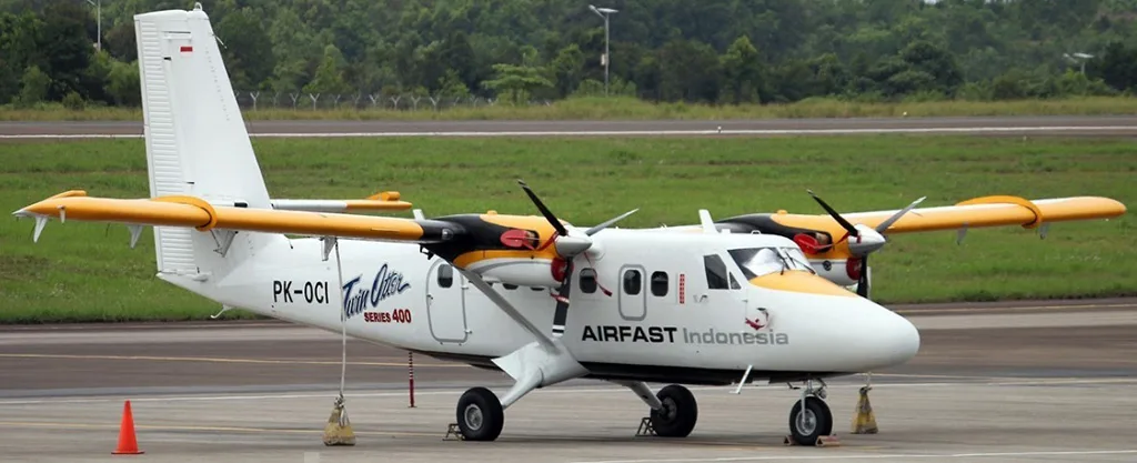 A white and yellow Airfast Indonesia Twin Otter Series 400 aircraft (PK-OCI) parked on an airfield.
