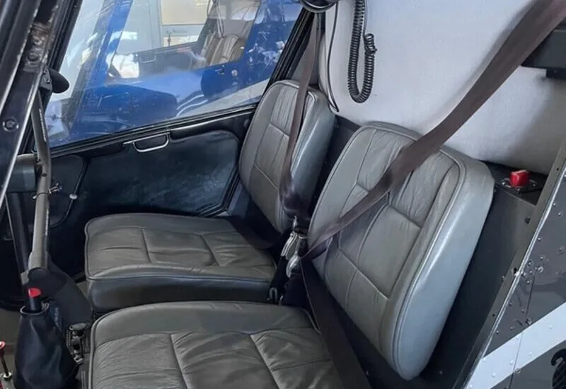 Interior view of the cockpit of a helicopter, showing the seats and seatbelts.