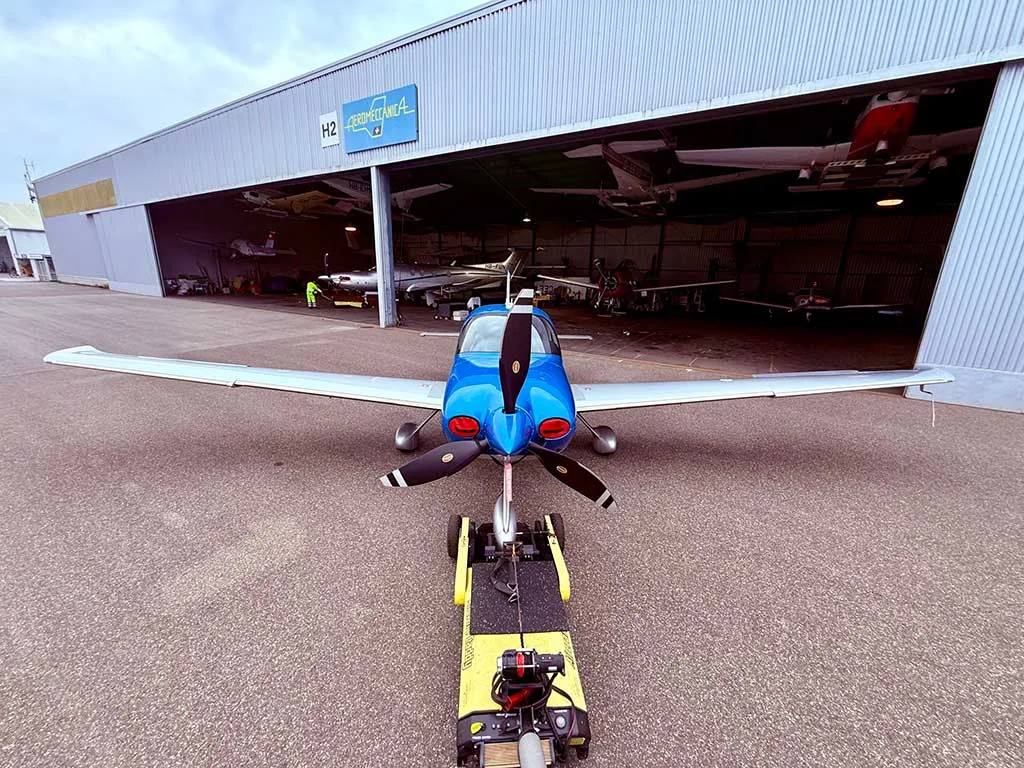 A front view of a blue and silver Cirrus SR22T aircraft being towed out of a hangar.