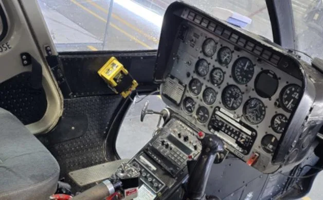A close-up view of a helicopter's instrument panel and controls, showing various gauges and switches.