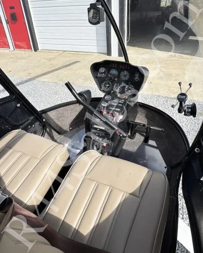 The tan leather seats and a partial view of the instrument panel inside a Robinson R22 helicopter.